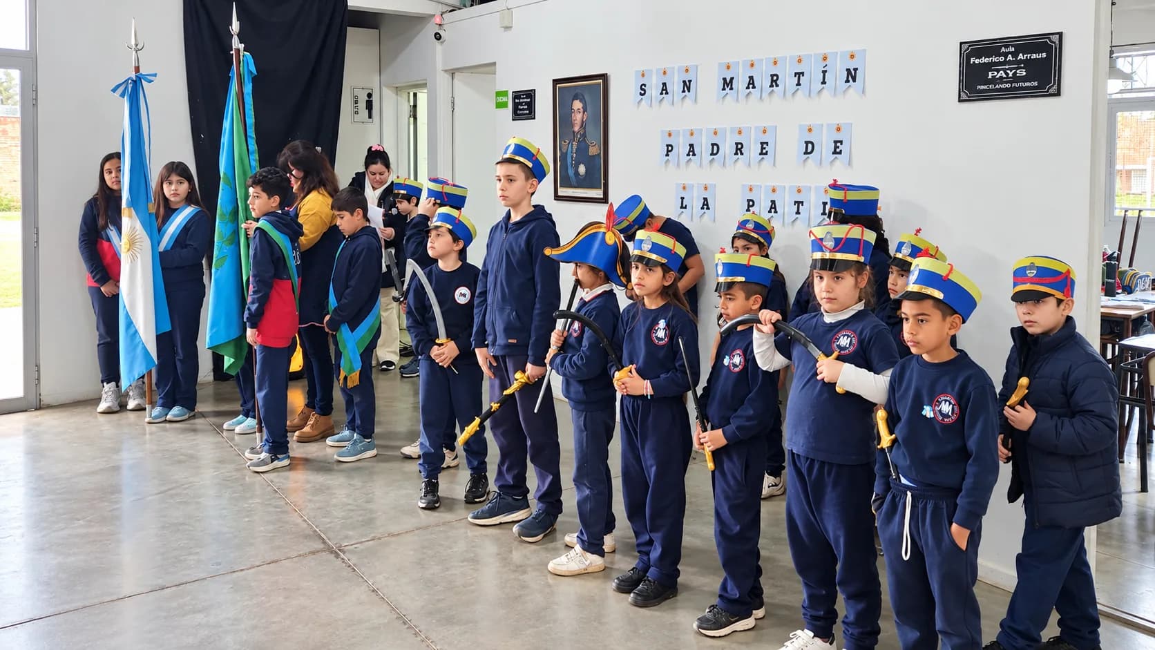 Alumnos formados con gorros de granadero, junto a las abanderadas